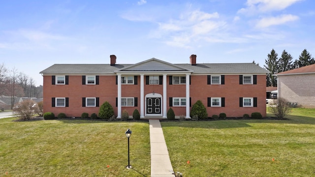 neoclassical home featuring a front lawn and a chimney