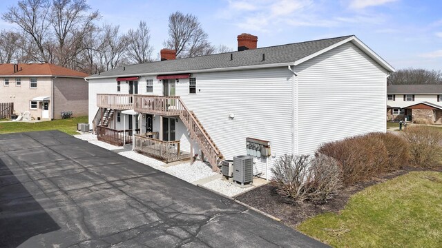 rear view of property with stairs, a wooden deck, central AC unit, and a chimney