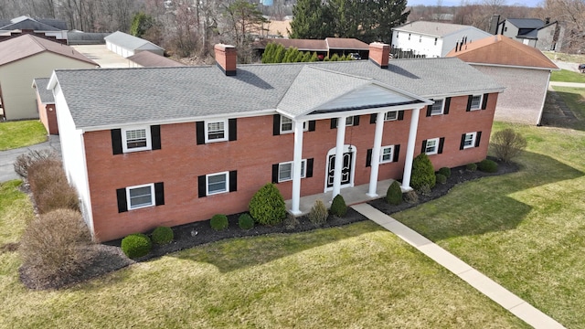 greek revival inspired property with a front lawn, a residential view, roof with shingles, and a chimney