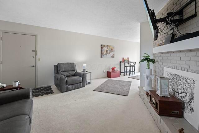 living room featuring a fireplace, a textured ceiling, and carpet