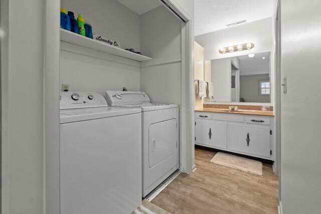 washroom featuring light wood finished floors, laundry area, independent washer and dryer, and a sink