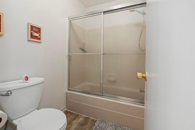 full bath with combined bath / shower with glass door, toilet, and wood finished floors