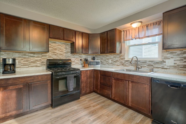 kitchen with a sink, light countertops, and black appliances