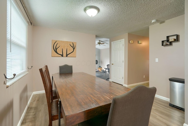 dining area featuring a textured ceiling, baseboards, a ceiling fan, and wood finished floors