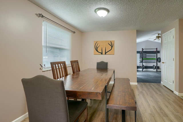 dining space with baseboards, a textured ceiling, light wood finished floors, and a ceiling fan
