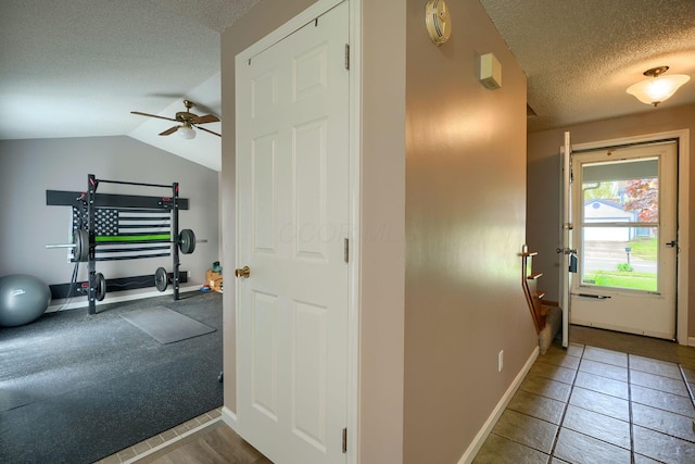 interior space featuring baseboards, tile patterned floors, a textured ceiling, and lofted ceiling