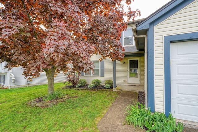 view of exterior entry with a garage and a yard