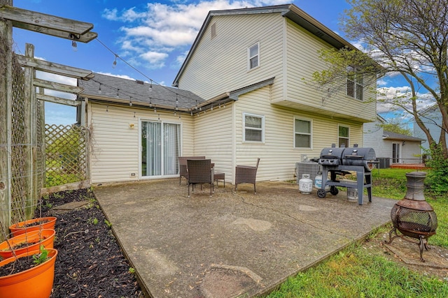 back of property with a patio, fence, a shingled roof, and a fire pit