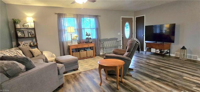 living room featuring dark wood-style floors, visible vents, baseboards, and a ceiling fan