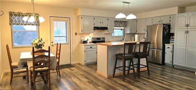 kitchen featuring dark wood-style floors, light countertops, under cabinet range hood, appliances with stainless steel finishes, and a center island