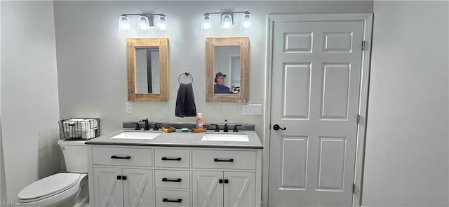 bathroom with double vanity, toilet, and a sink
