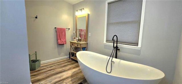 full bath featuring a freestanding tub, baseboards, and wood finished floors