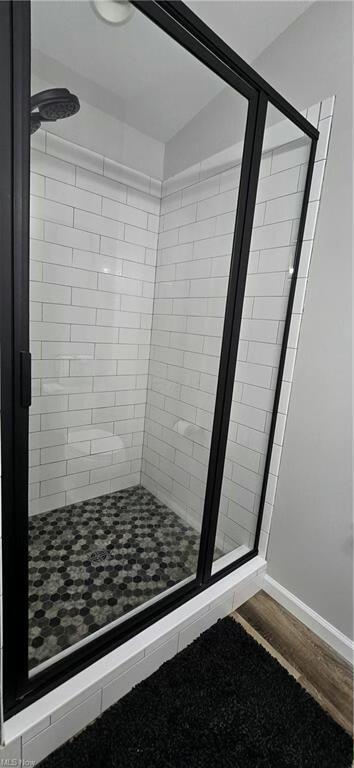bathroom featuring baseboards, wood finished floors, and a shower stall