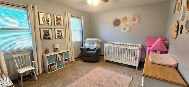 bedroom featuring a crib, carpet, and a ceiling fan
