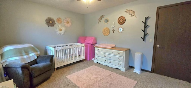 bedroom with baseboards, a crib, and carpet