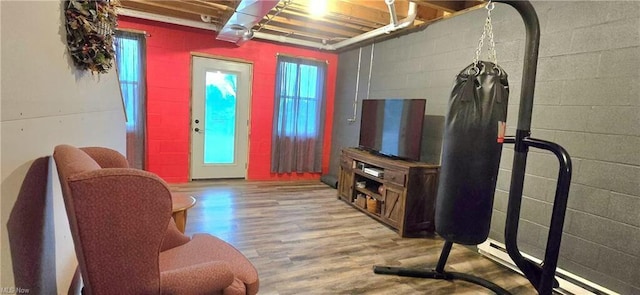 living area with a wealth of natural light, wood finished floors, and concrete block wall
