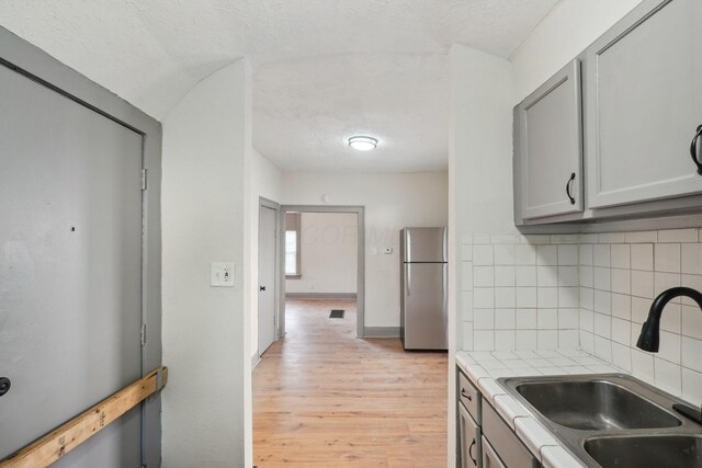 940 Leona Ave, Columbus, OH 43201 - kitchen with freestanding refrigerator, a sink, light wood-style flooring, backsplash, and gray cabinetry