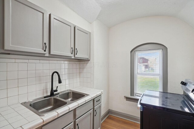 940 Leona Ave, Columbus, OH 43201 - kitchen featuring stainless steel electric range, tile countertops, a sink, decorative backsplash, and light wood-type flooring