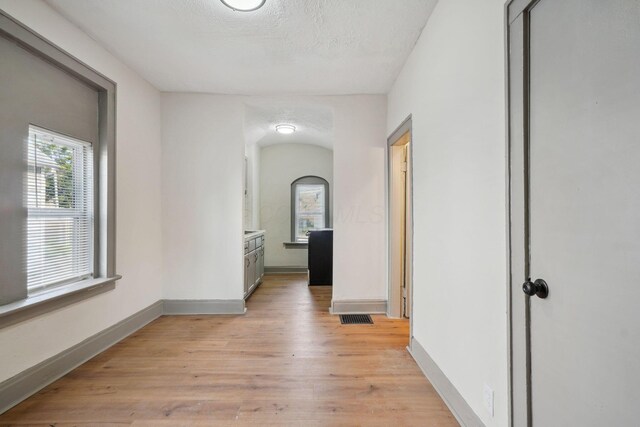 940 Leona Ave, Columbus, OH 43201 - hallway with arched walkways, light wood-type flooring, baseboards, and a textured ceiling