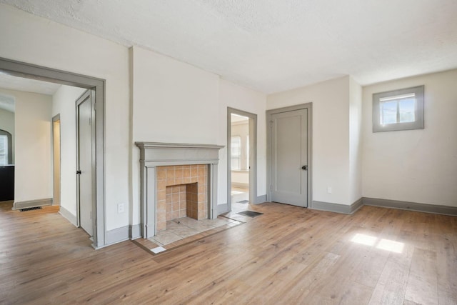 940 Leona Ave, Columbus, OH 43201 - unfurnished living room featuring wood finished floors, a tiled fireplace, and baseboards