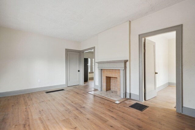 940 Leona Ave, Columbus, OH 43201 - unfurnished living room featuring light wood-type flooring, baseboards, and a tiled fireplace