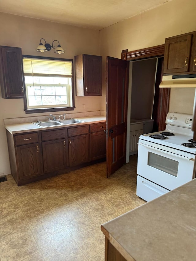 kitchen with light countertops, under cabinet range hood, a sink, and electric range