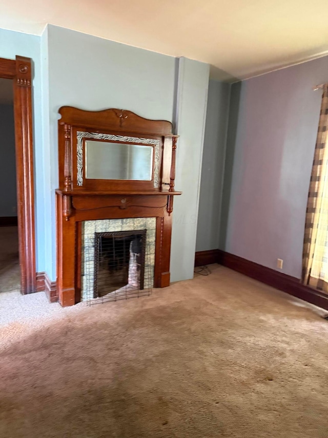 unfurnished living room with baseboards, a fireplace, and carpet