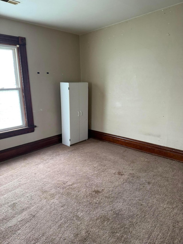 spare room with carpet floors, baseboards, and visible vents