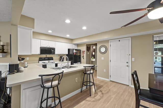 2983 Glenloch Cir, Dublin, OH 43017 - kitchen with a peninsula, black appliances, light countertops, a sink, and a breakfast bar area