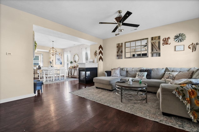 living area featuring baseboards, visible vents, wood finished floors, and ceiling fan with notable chandelier