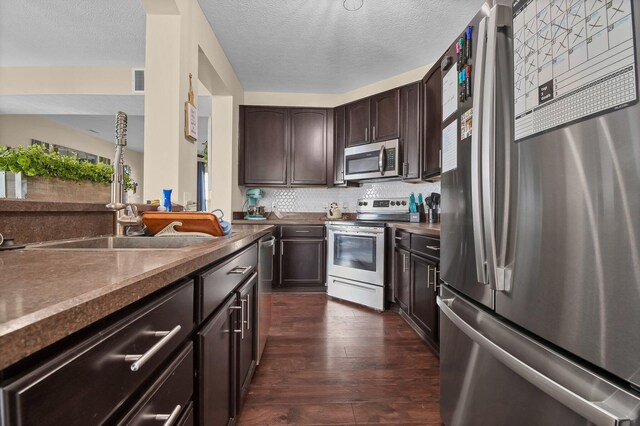 kitchen with a sink, tasteful backsplash, appliances with stainless steel finishes, dark wood-style floors, and dark brown cabinets
