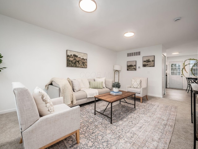 living room featuring visible vents, light colored carpet, and baseboards
