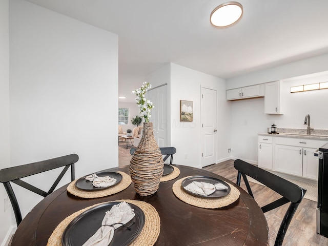 dining area featuring indoor wet bar, baseboards, and light wood finished floors