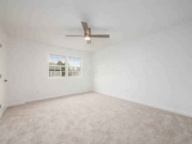 carpeted spare room featuring baseboards and ceiling fan