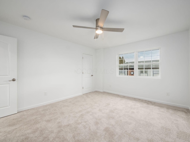carpeted spare room featuring a ceiling fan and baseboards