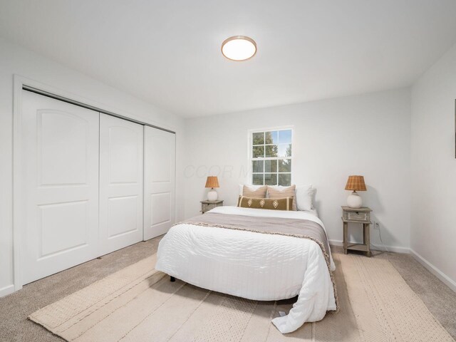 carpeted bedroom featuring a closet and baseboards