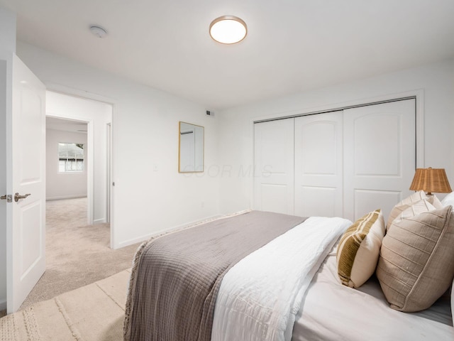 bedroom featuring light colored carpet, a closet, and baseboards