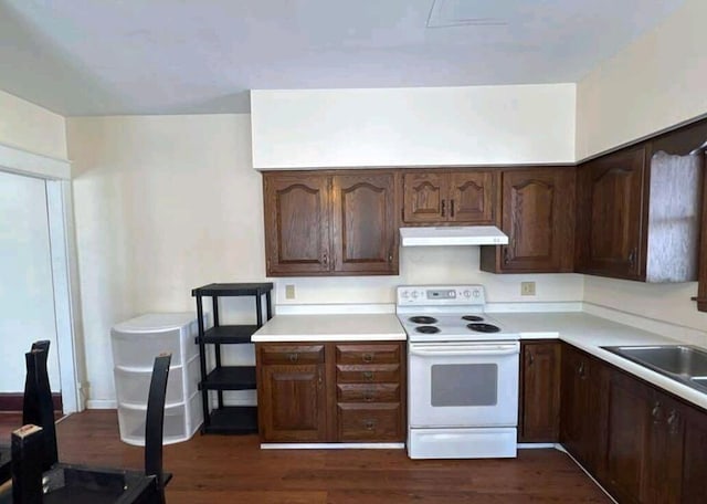 kitchen featuring under cabinet range hood, dark wood finished floors, light countertops, white electric stove, and a sink