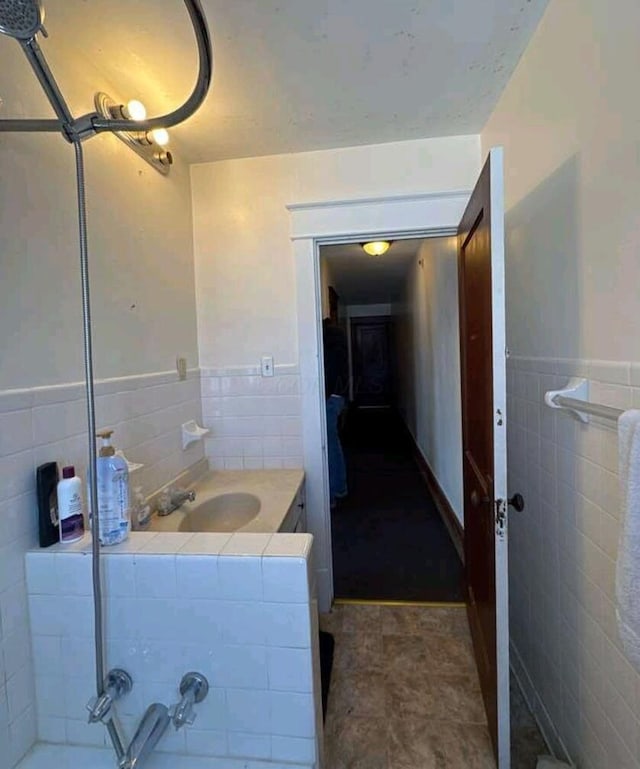 full bath with vanity, tile walls, a bath, and wainscoting