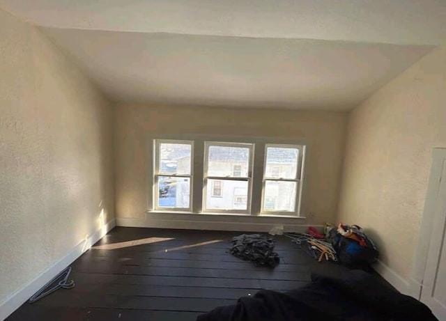 interior space with a textured wall, baseboards, and hardwood / wood-style flooring