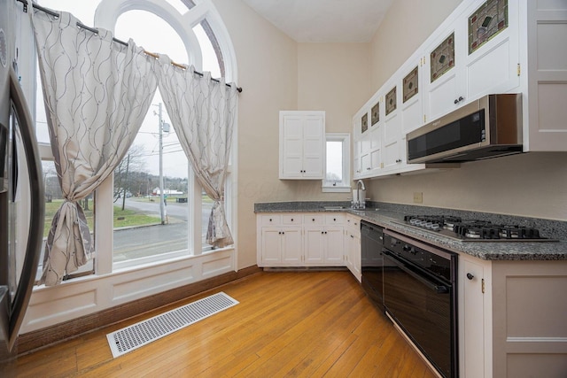 108 W Main St, Glenford, OH 43739 - kitchen with visible vents, light wood-style flooring, black appliances, white cabinets, and glass insert cabinets