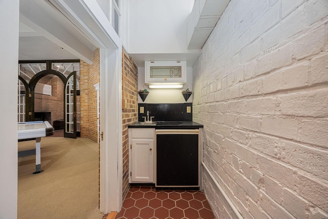 108 W Main St, Glenford, OH 43739 - kitchen with a sink, dark countertops, white cabinetry, brick wall, and dishwashing machine