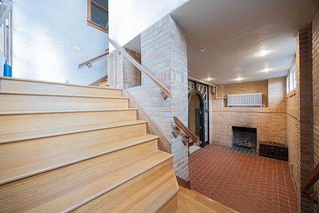 108 W Main St, Glenford, OH 43739 - stairs with arched walkways, brick wall, a fireplace, and a textured ceiling