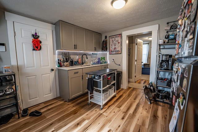 kitchen with light wood-style flooring, gray cabinets, and a sink