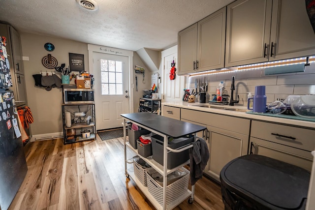 kitchen featuring light wood-style floors, visible vents, backsplash, and a sink