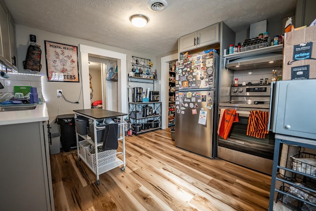 kitchen with visible vents, open shelves, light countertops, light wood-style floors, and appliances with stainless steel finishes