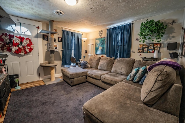 living area with wood finished floors, visible vents, and a textured ceiling