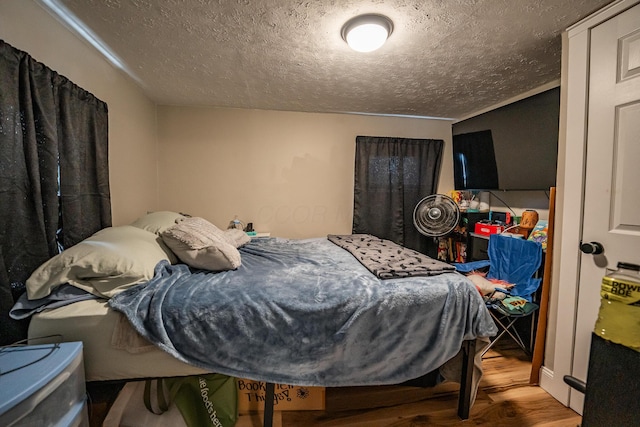 bedroom with a textured ceiling and wood finished floors