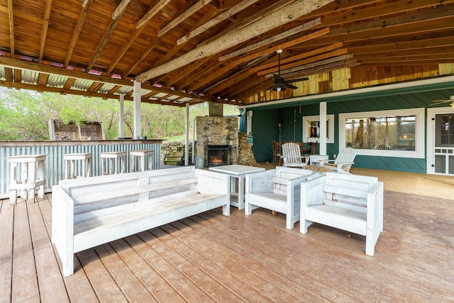 wooden terrace with outdoor dry bar, a ceiling fan, and an outdoor stone fireplace
