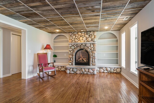 living area with a fireplace, hardwood / wood-style flooring, built in features, and baseboards